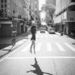 grayscale photo of woman walking on pedestrian lane